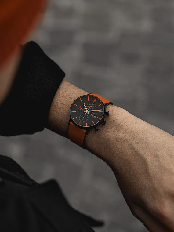 The Junghans FORM A Chronoscope Watch is a watch that features a chronograph, a day date function, and a luminescent coating on the hands and indexes. It has a 43mm black and orange dial and an ergonomic, smooth, curving shape. The watch also has a date aperture at the 3 o'clock position.